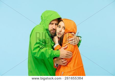 The Young Couple Posing At Studio In Autumn Jacket Isolated On Blue. Human Negative Emotions. Concep