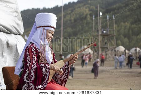 Lake Issyk-kul, Kyrgyzstan, 6th September 2018: Local Lady In Full Kyrgyz Outfit, Playing Komuz, The