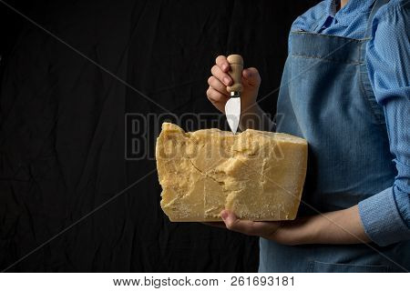 Woman Holding Knife And A Slice Of Parmesan Cheese On Black Background