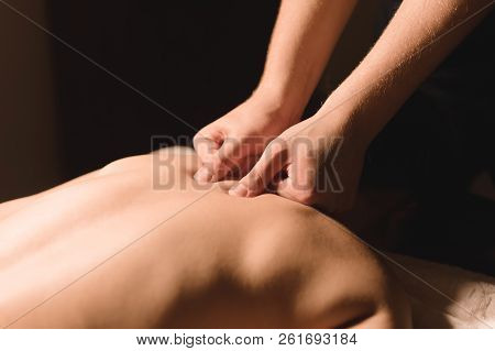 Men's Hands Make A Therapeutic Neck Massage For A Girl Lying On A Massage Couch In A Massage Spa Wit
