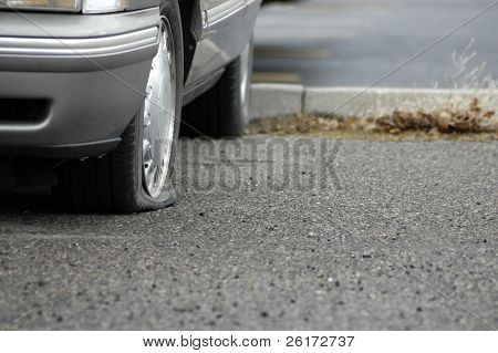Auto parcheggiata su una carreggiata con una gomma a terra