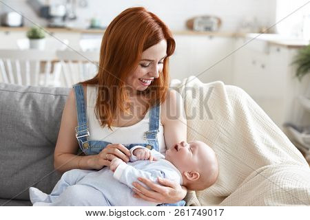 Happy Motherhood Concept. Picture Of Cute Joyful Young European Mom With Ginger Hair Babysitting Ado