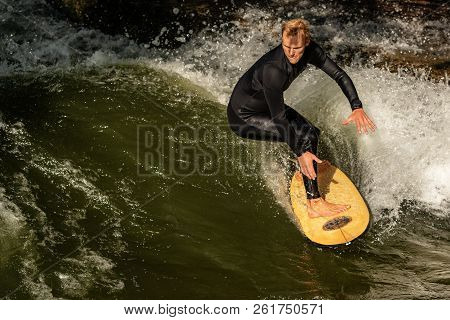 Munich, Germany - Sept 8, 2018: A Man Surfing In The Waves Of The Eisbach River In Downtown Of Munic