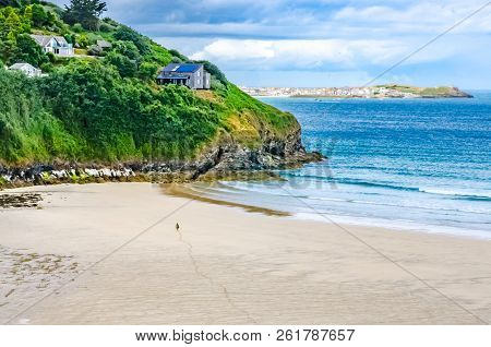 Sandy Beach, Cliff And See In Cornwall. Tranquil Setting With Figure Walking Pin Beach