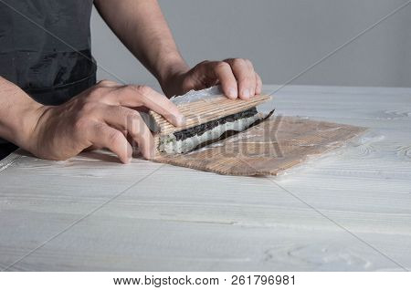 Process of making maki sushi. Cook chef hands preparing rolls with cheese, avocado and sesame seeds 