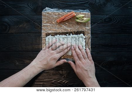 Process of making maki sushi. Cook chef hands preparing rolls with cheese, avocado and sesame seeds