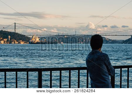 A Young Boy Watches The Scenery At The Pier.
