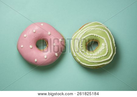 Donuts On Turquose Background With Green, Pink Icing And White Sugar Decorations