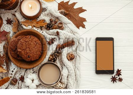 Stylish Autumn Flat Lay. Phone With Empty Screen And Coffee,cookies, Leaves, Candle, Nuts, Acorns, C
