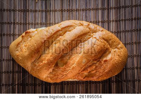 Bun On A Straw Brown Litter.
Freshly Baked Loaf Of Bread On A Straw Mat.