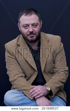 Portrait Of Sitting Man With Yellow Jacket And Black Shirt