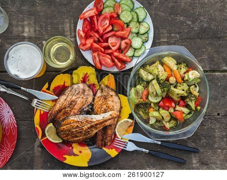 Three Grilled Salmon Steaks With A Side Dish Of Baked Vegetables