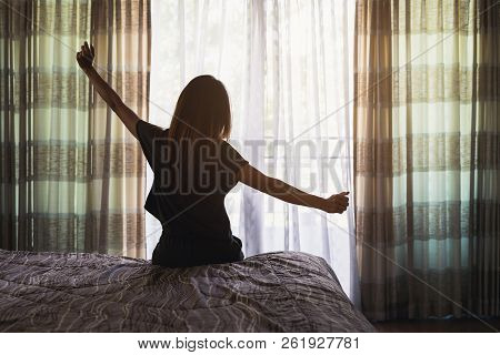 Young Asian Woman Sitting On The Bed And Stretch Oneself In The Morning