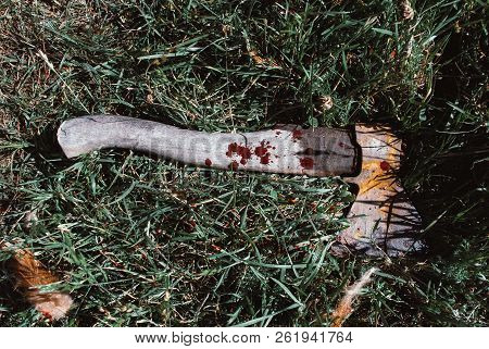 A Bloodstained Ax On The Grass. Realistic Blood. The Background