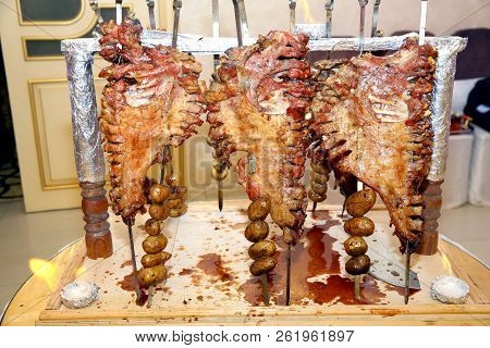 Barbecue Is Prepared Of Lamb Or Sheep Meat And Processed By Slasher. Roasted Meat Over An Open Fire,