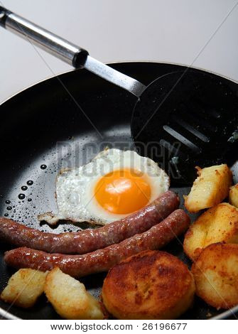 Egy serpenyőben, egy magas kalóriatartalmú reggeli kolbász, sült burgonya, sült tojás.