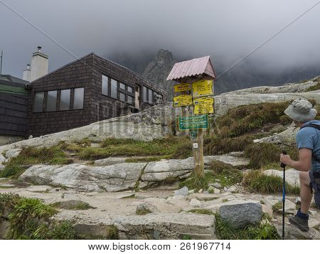 Slovakia, High Tatra Mountain, September 13, 2018: Young Men Hiker Looking At Trail Signpost In Fron