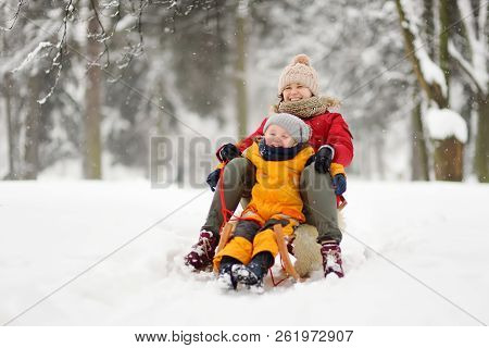 Little Boy And Mother Sliding In The Park During A Snowfall. Outdoor Winter Activities For Family Wi