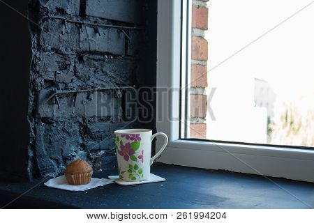 A Cup With Tea And Cupcake Near The Window