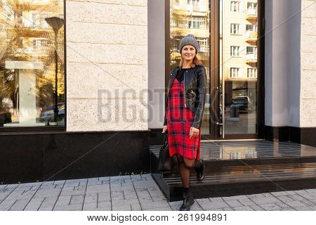 Young Female Student In Warm Autumn Clothes Coming Out Of The House With A Backpack With Books  Arou
