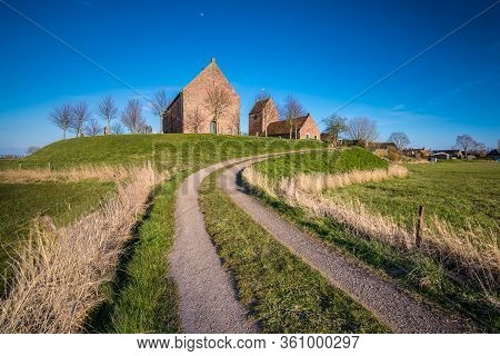 The Historical Medieval Church Of The Small Dutch Village Of Ezinge Under A Blue Sky And A Rural Roa