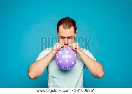 A Man Is Inflating The Balloon. A Man With Beard On The Blue Background. A Man With Closed-eyes Is B