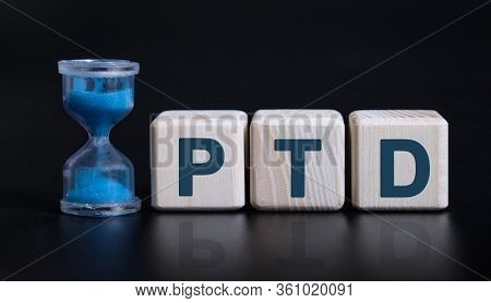 Ptd - Project To Date Acronym Concept With An Hourglass. Wooden Cubes On A Black Table