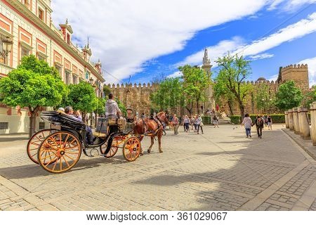 Seville, Andalusia, Spain - April 18, 2016: Tourists Making A Horse Carriage Ride In Triumph Square 
