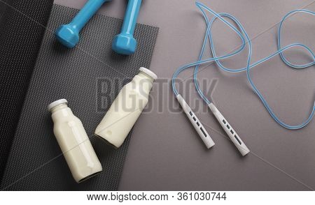 Fitness Background. Equipment For Home. Jump Rope, Dumbbells, Mat, Detox Water On Gray Background