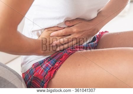 Detail Of A Woman Dressed On White T-shirt And Red And Blue Checked Shorts Sitting And Holding Her A