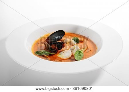 Bouillabaisse in white bowl. Served main course close up. French seafood, soup with fish and mussels. Restaurant food portion, main course. France cuisine. Dinner, gourmet meal in plate