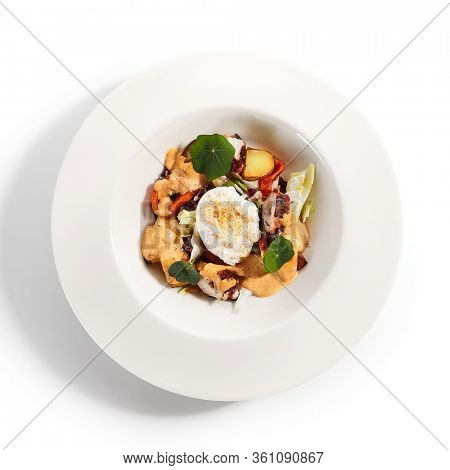 Salad in white bowl. Sliced octopus and fried potato. Served cut ingredients with mayonnaise, tomato spicy ajika and smoked pepper homemade sauce. Restaurant food portion in plate close up