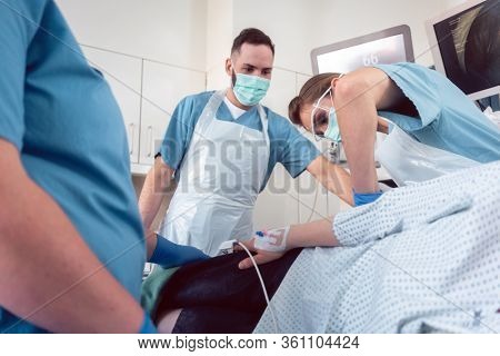 Doctor in surgery of hospital performing colonoscopy at sedated patient