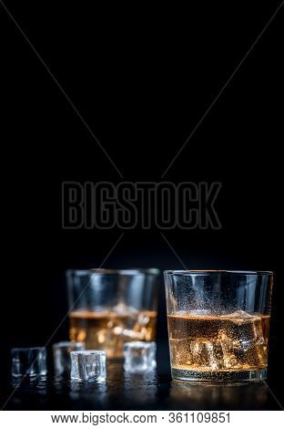 Whisky, Whiskey, Bourbon Or Cognac With Ice Cudes On Black Stone Table