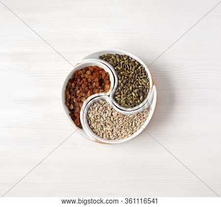 Peeled Sunflower Seeds, Pumpkin Seeds And Raisins Lie On A White Table In A Beautiful Round Plate Di