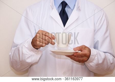 Concept - A Doctor In A White Coat Holding A Cup Of Coffee In His Hand