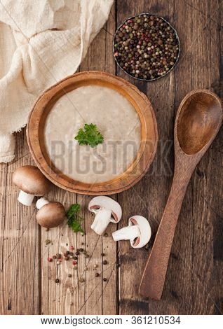 Wooden Plate Of Creamy Chestnut Champignon Mushroom Soup With Wooden Spoon, Pepper And Kitchen Cloth