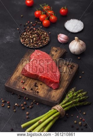 Slice Of Raw Beef Sirlion Steak On Wooden Chopping Board With Tomatoes,garlic And Asparagus Tips On 