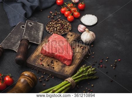 Slice Of Raw Beef Sirlion Steak On Wooden Chopping Board With Tomatoes,garlic And Asparagus Tips And