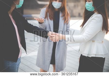 Businesswomen Shaking Hands With People In The Background. Two Confident Businesswomen Shaking Hands
