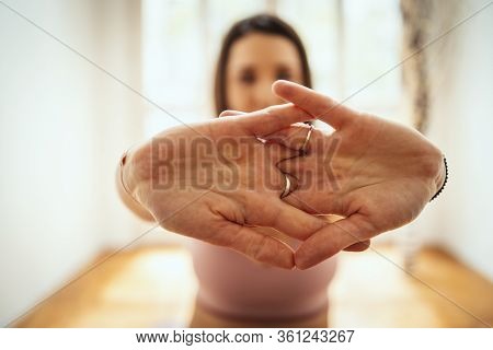 Young Woman Is Doing Yoga Meditation In The Living Room At Home. She Is Meditating On Floor Mat In M