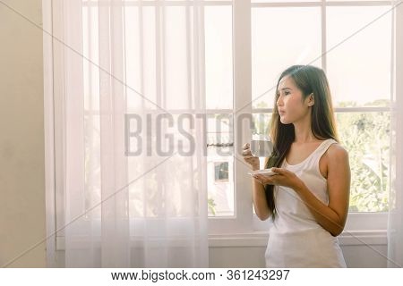 Young Asian Woman Having A Cup Of Coffee. She Stay Isolation At Home For Self Quarantine. Corona Vir