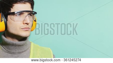 Studio Close-up Portrait Of Young Airport Worker, Engineer Mechanic, Isolated On Background Of Aqua 