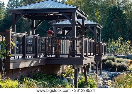 A Gazebo Attatched To A Wooden Deck In Beautiful Garden
