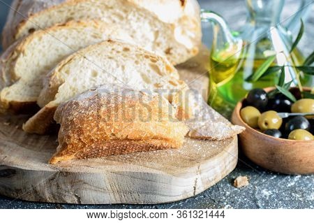 Slices Of White Homemade Bread On The Wooden Kitchen Cutting Board, Olive Oil Bottle And Olves In Bo