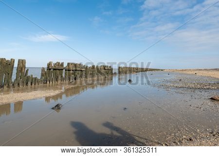 The Wadden Sea At Paesens Moddergat, Wooden Poles, Sea And Sky.