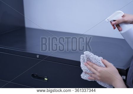 Young Woman Is Holding Spray Bottle, Rag To Clean, Wipe Down Office Metal Cabinet Shelf Accommodatio