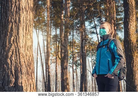 Young Woman In Medical Mask Walks In A Spring Pinewood. Spring.