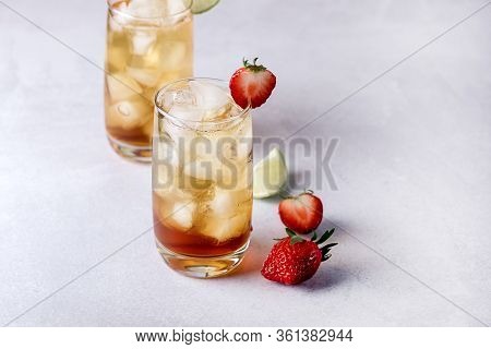 Glasses Of Cold Citrus And Strawberry Ice Tea On Light Gray Background Decorated With Ripe Lime And 