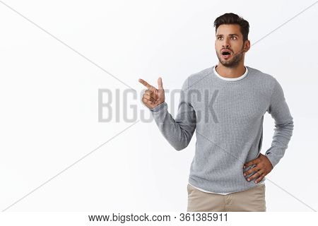 Shocked Slightly Worried Handsome Bearded Caucasian Guy In Grey Trendy Sweater, Gasping Drop Jaw Fro